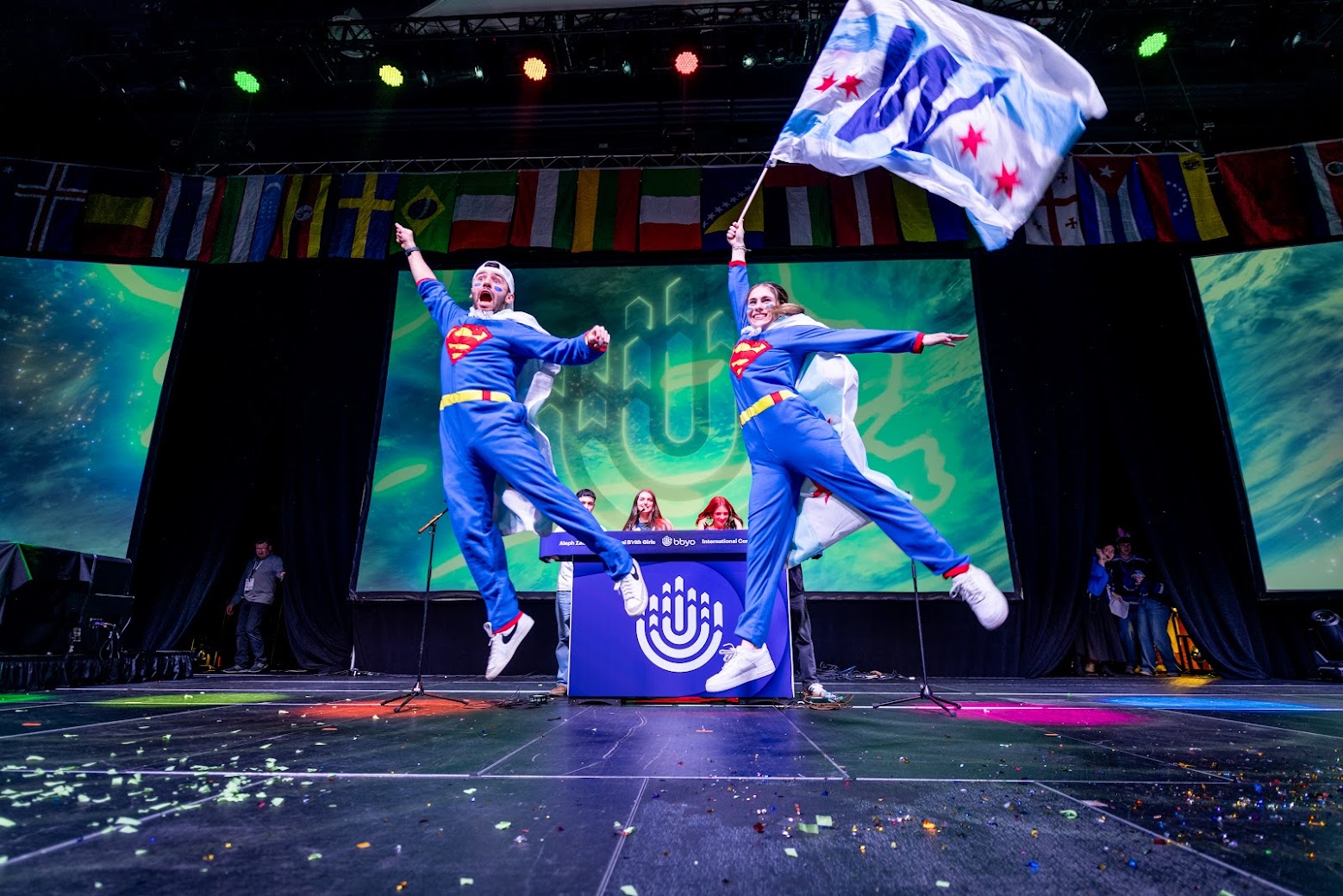 קהל מגוון של אנשים החוגגים בהופעה, מרימים ידיים ומריעים.